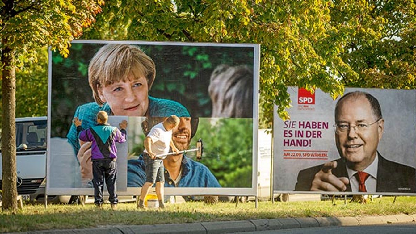 Workers paste up election poster showing CDU top candidate in upcoming German general elections, German Chancellor Merkel, in Berlin