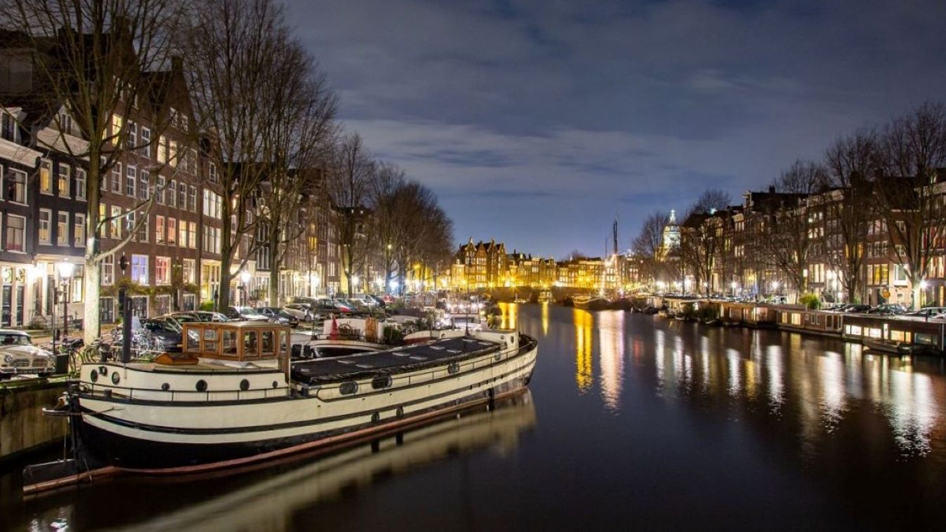 Canals in Amsterdam like Amstel with typical traditional old dutch architecture houses illuminated and houseboats in the evening and night with beautiful water reflections and city lights, Holland, Netherlands.