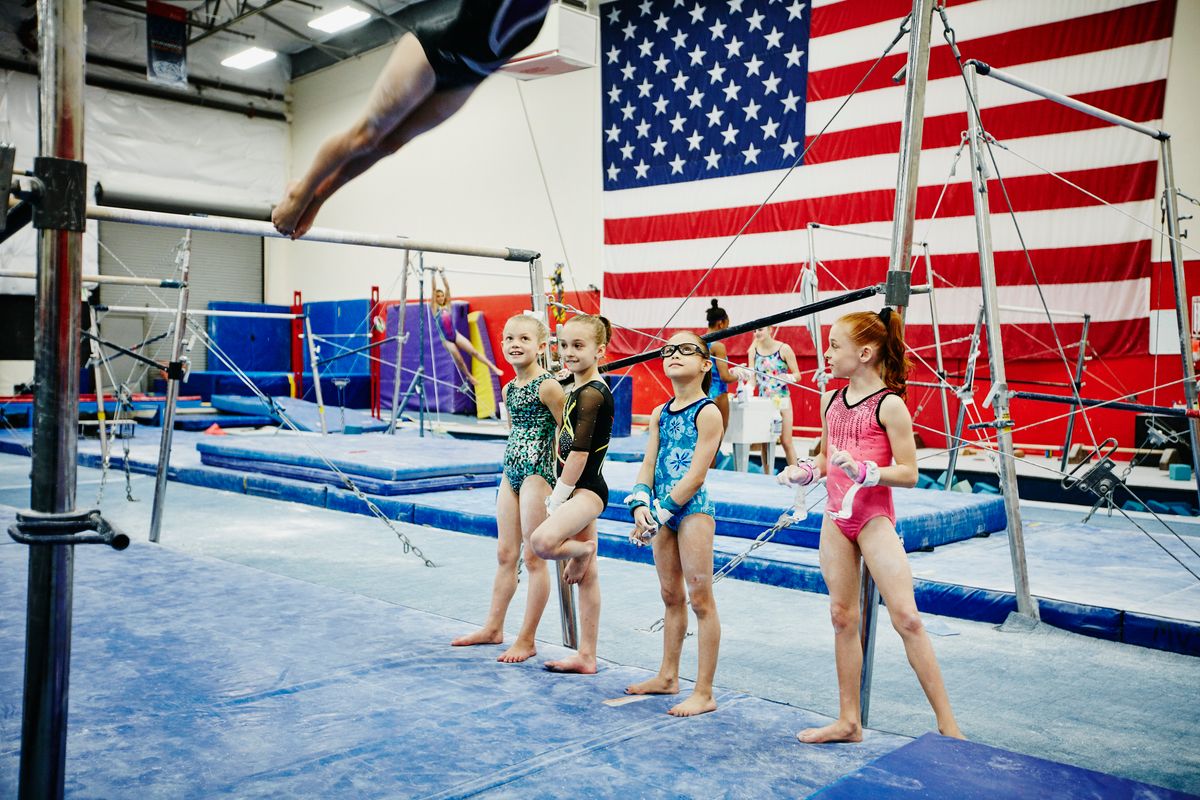Young gymnasts watching teammate practice on bars