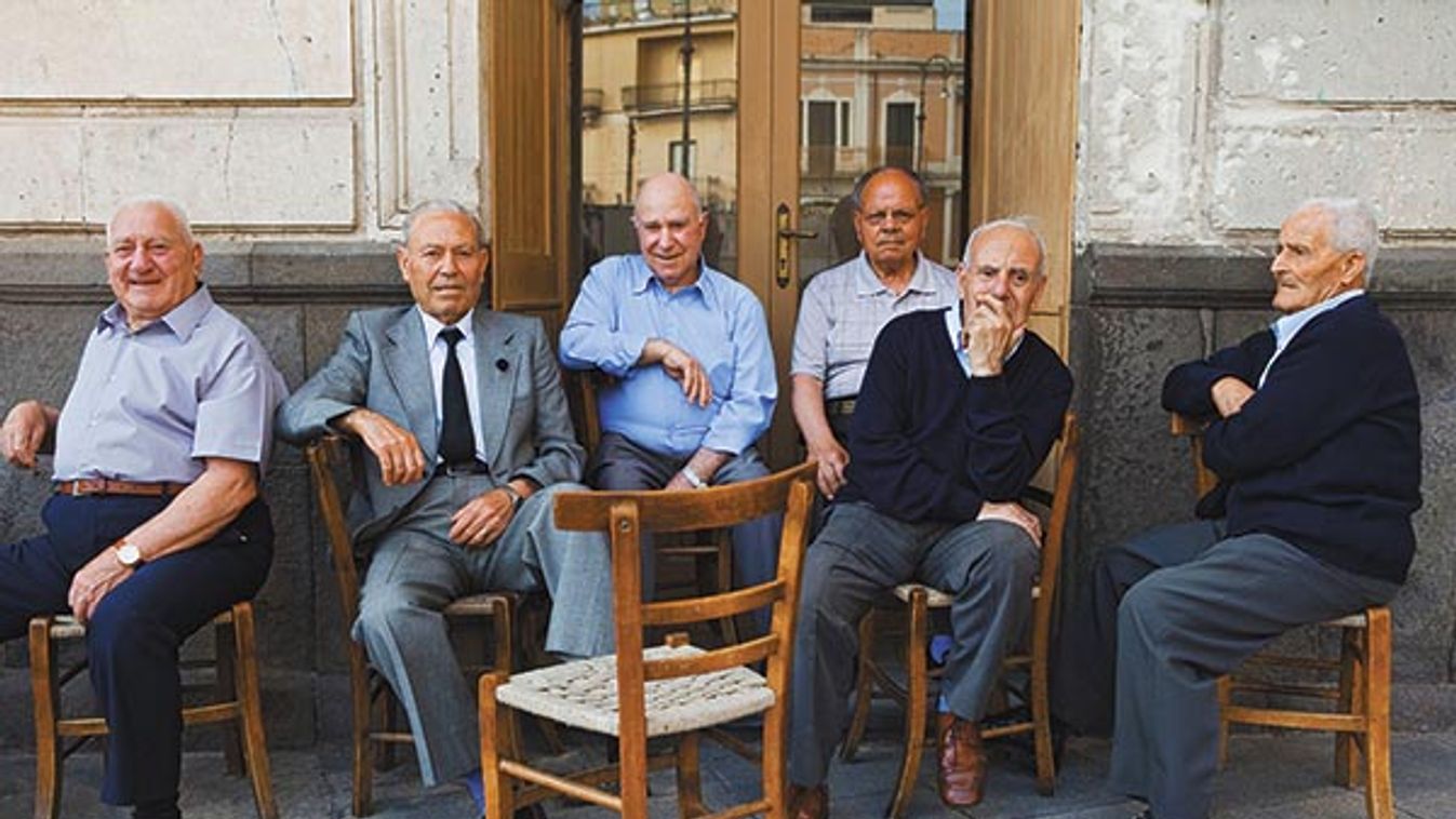 six old men sitting outside on chairs