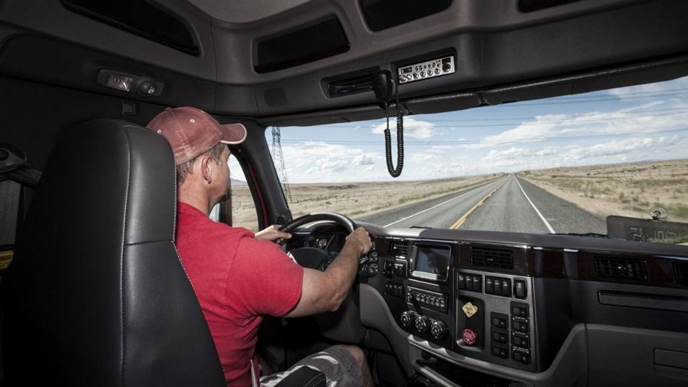 Interior cab view of a Caucasian man driving his commercial truck.