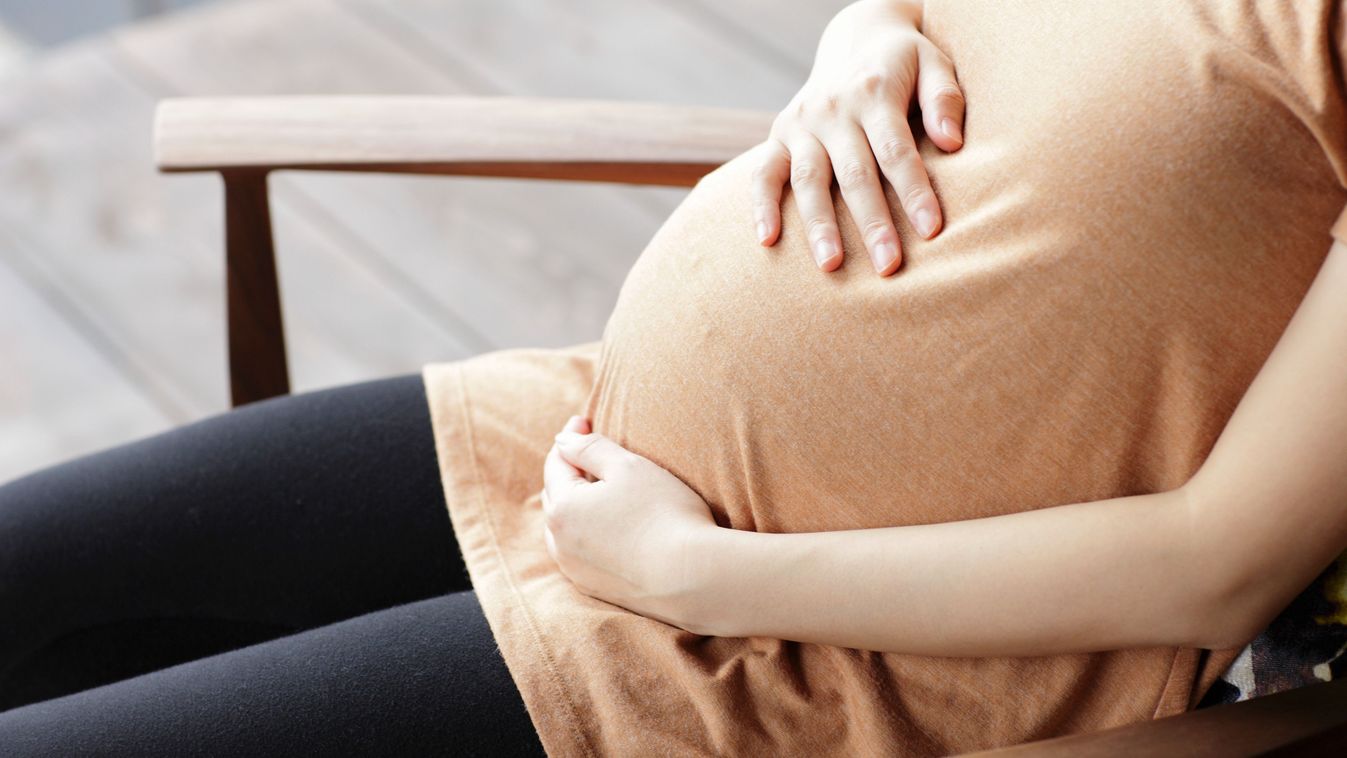 Pregnant woman touching abdomen sitting chair