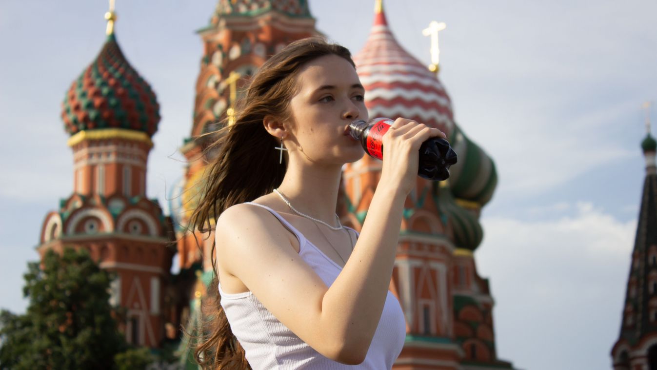 A Russian girl drinks Coca-Cola. 
The Coca-Cola company