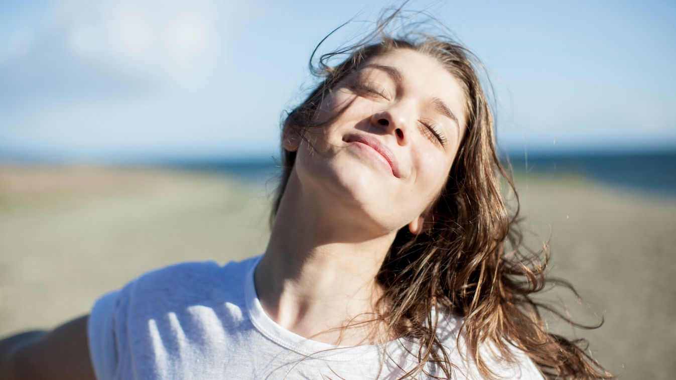 Young woman with eyes closed smiling on a beach