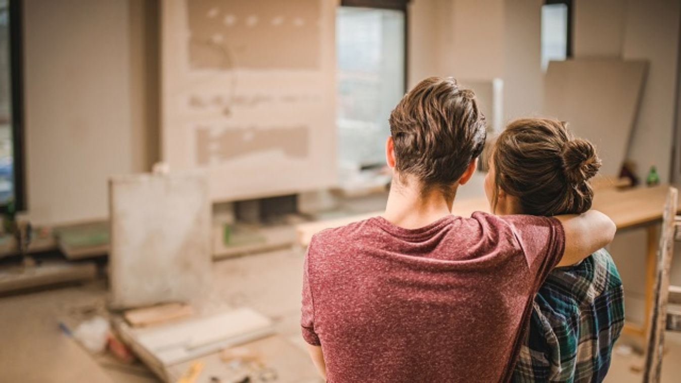 Back view of embraced couple in their renovating apartment.