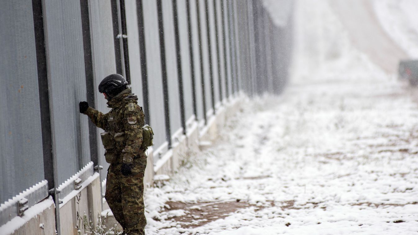 A border guard is seen guarding the border wall dividing