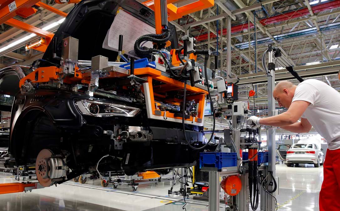 Factory workers inspect cars on the assembly line during the launch of a new factory of German premium car maker Audi in Gyor