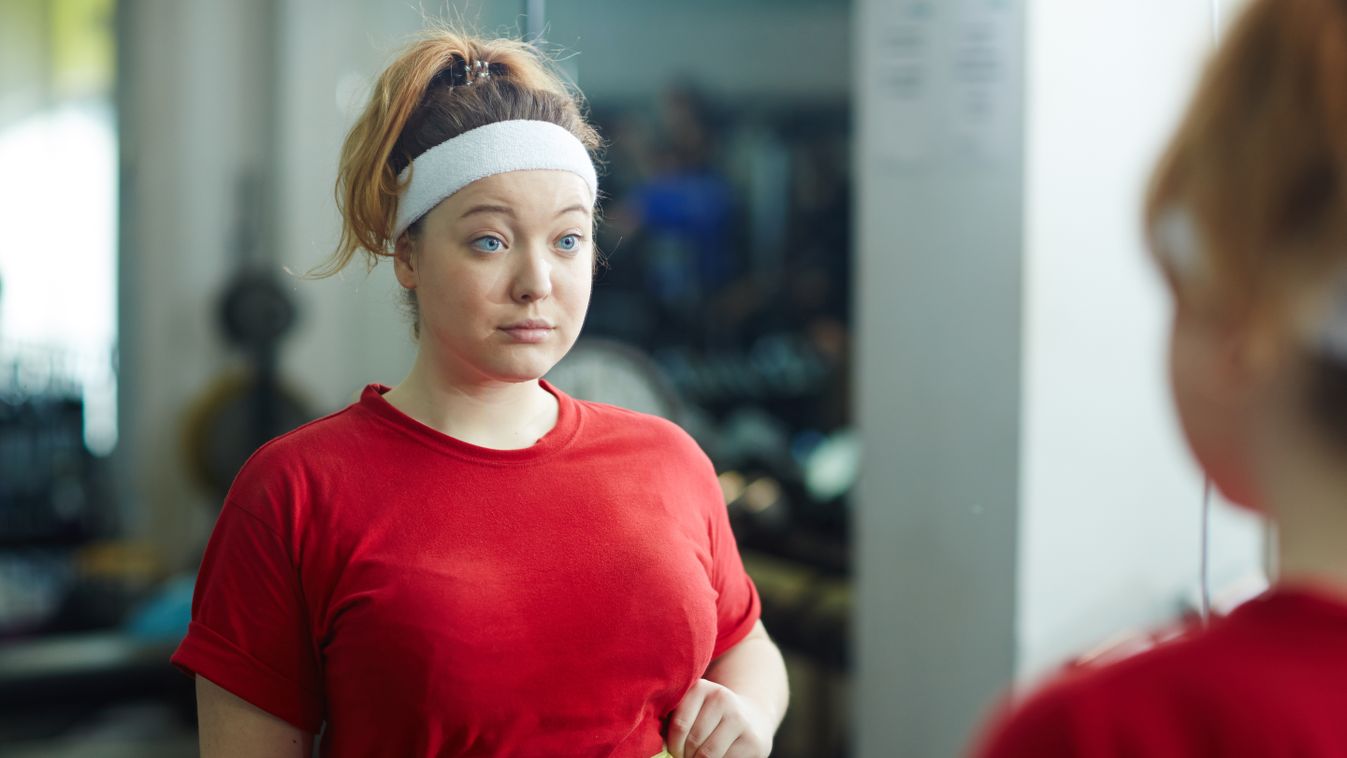 Portrait,Of,Cute,Obese,Woman,Standing,Against,Mirror,In,Gym