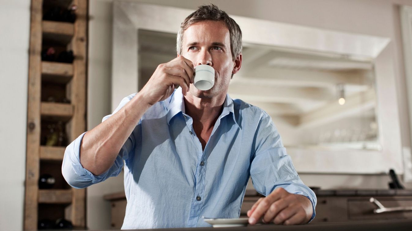 Germany, Hamburg, Man sitting at table, drinking cup of espresso