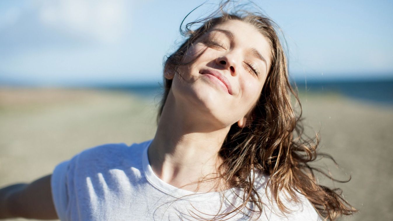 Young woman with eyes closed smiling on a beach