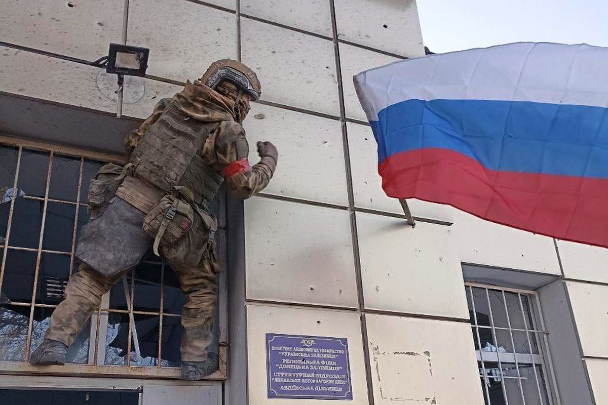 Az orosz hadsereg egyik katonája kitűzi az orosz zászlót Pokrovszk egyik középületére