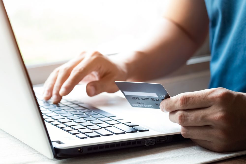 Cheerful,Young,Man,Paying,Bills,Online,With,Credit,Card,And